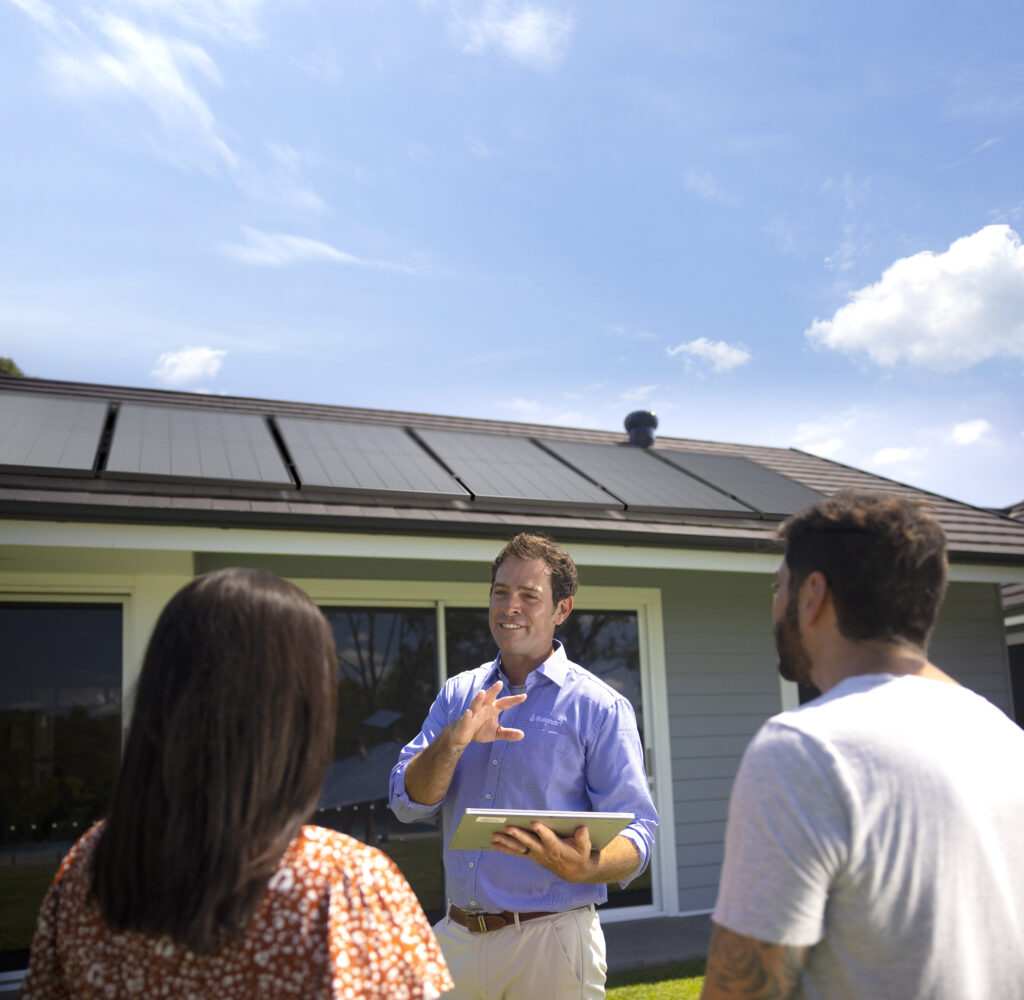 Solahart dealer explaining solar power to couple in front of house