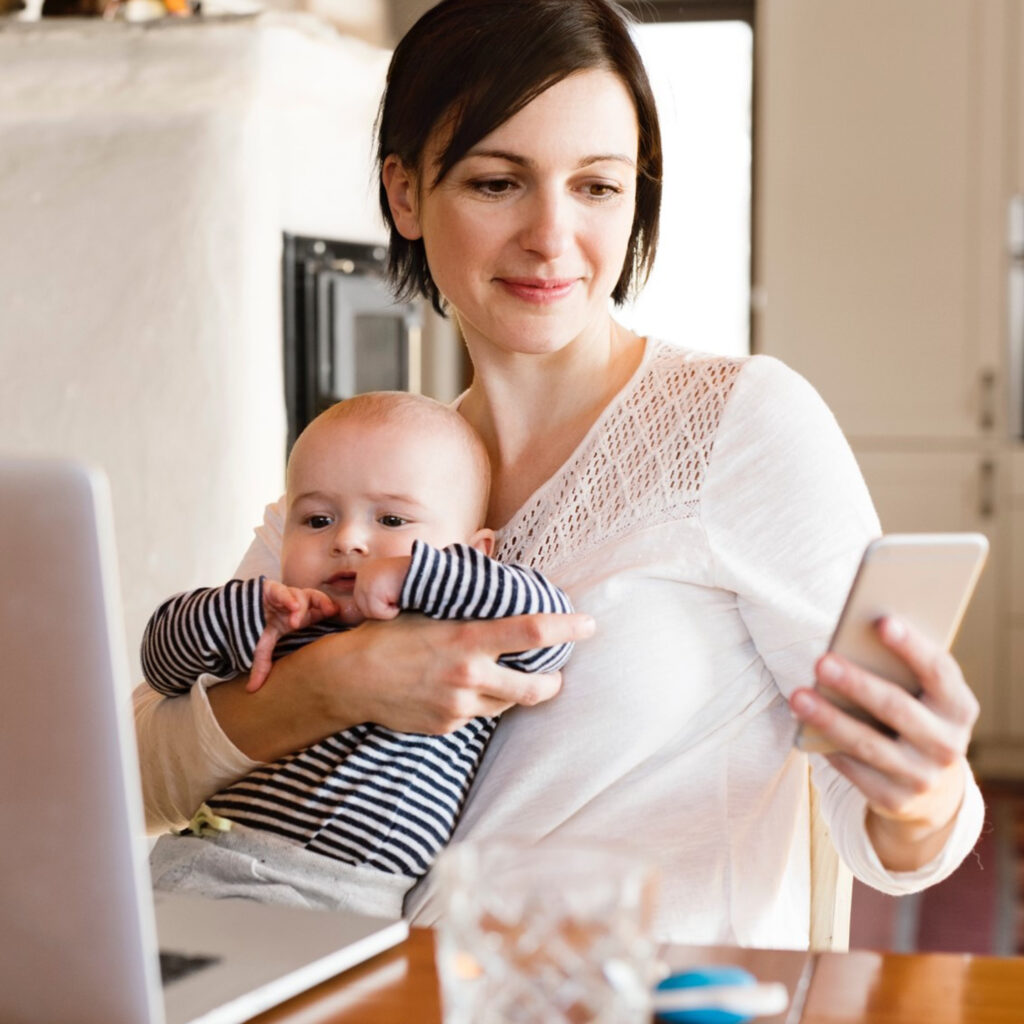 Mum holding baby and viewing her energy use on the Solahart Home Energy Management System mobile app